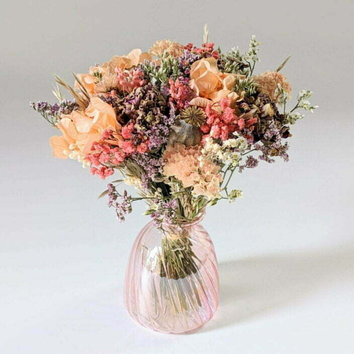 Petit bouquet de fleurs séchées dans son vase en verre teinté dans les tons roses et pêche, Blue