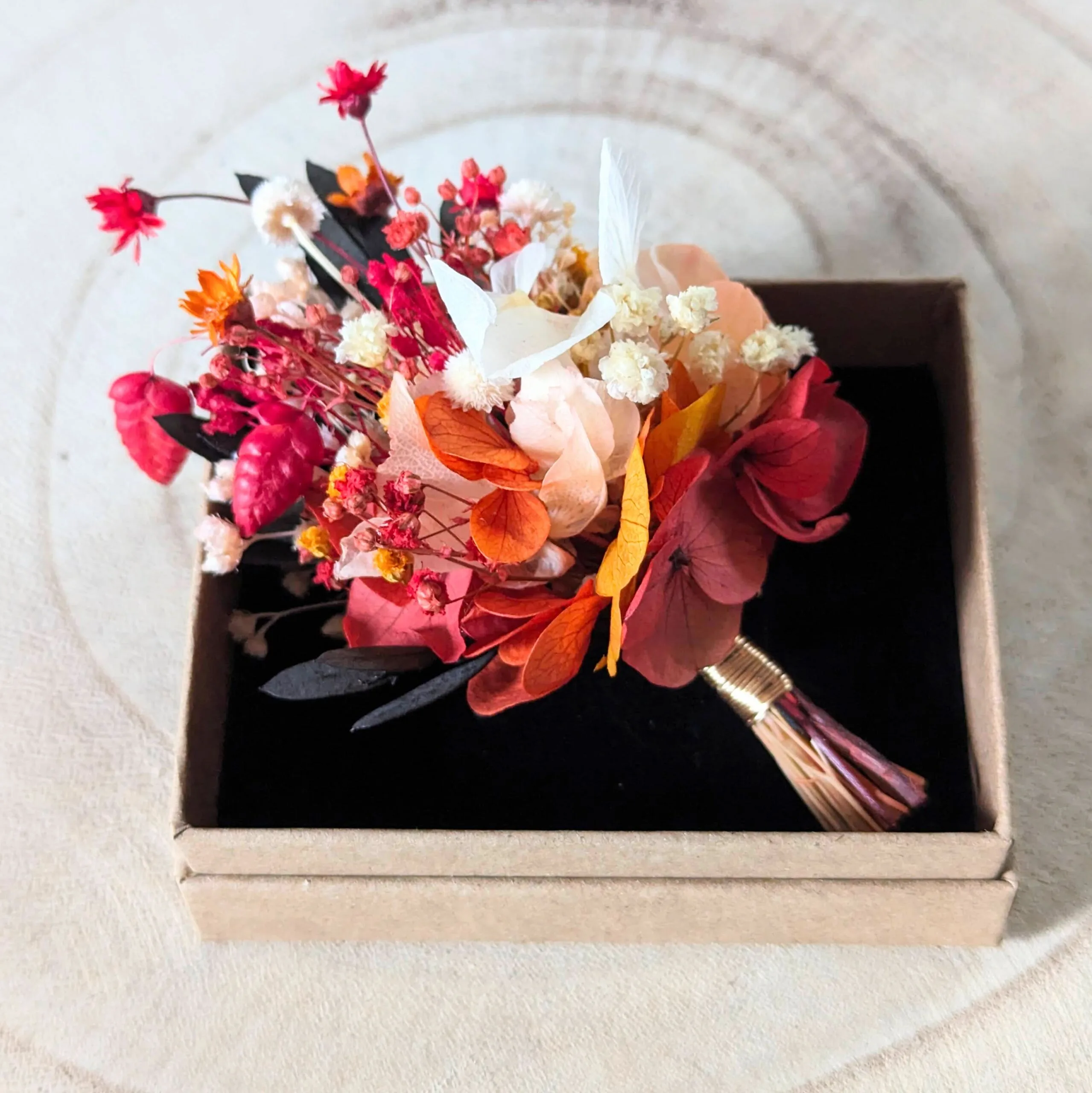 Boutonnière de marié artisanale fleurs stabilisées aux tonalités rouges, Coco Cinelle